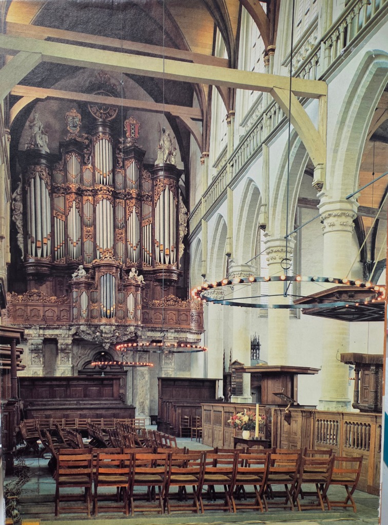 Interior of a historic church featuring an ornate pipe organ and wooden seating