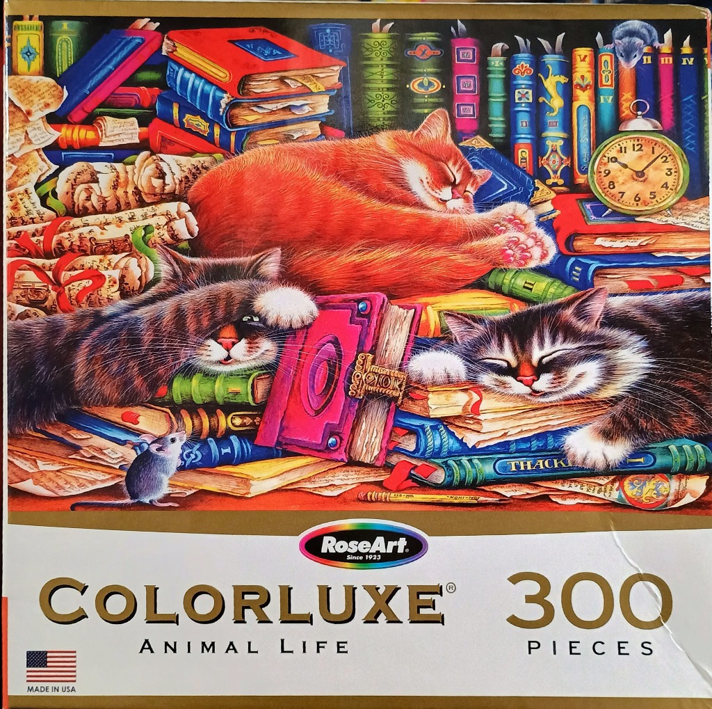 Three cats sleeping on a large stack of antique, colorful books with two small mice nearby.