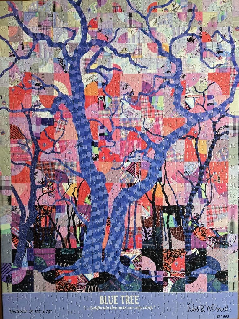 A stylized blue tree set against a background of a patchwork quilt made of various fabrics and patterns.