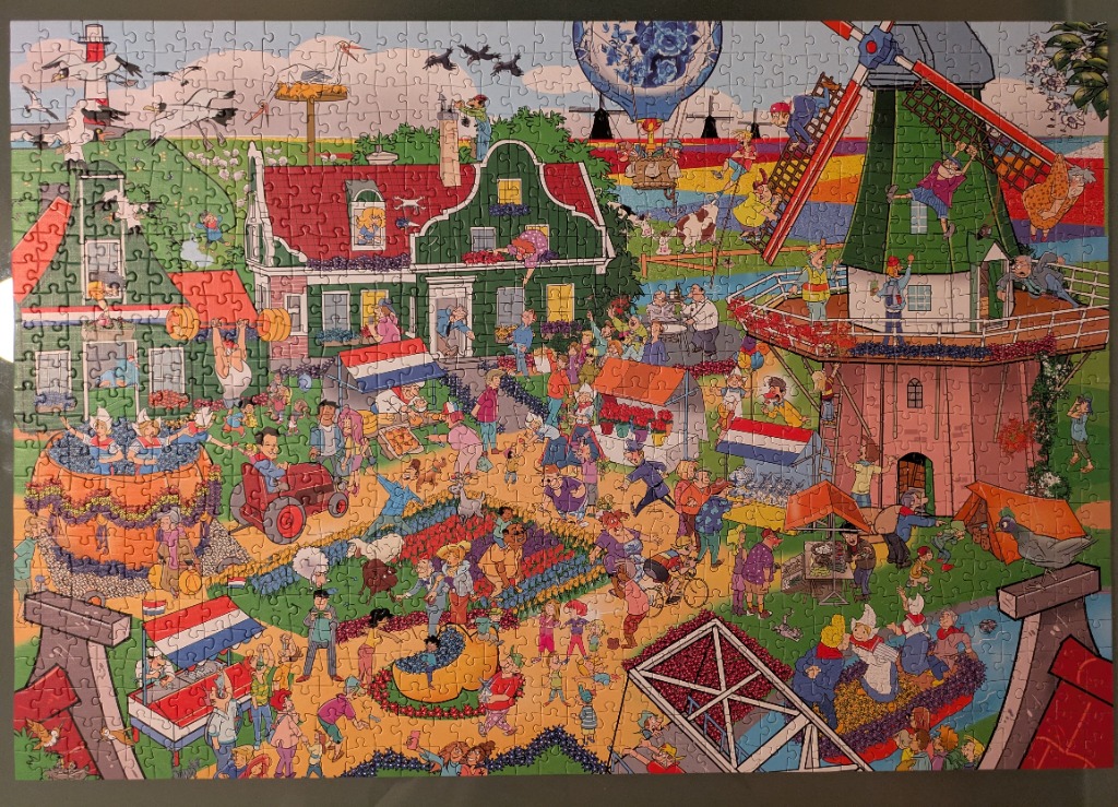 Cartoon illustration of a busy Dutch village scene featuring a windmill, traditional houses, and people in folk costumes.
