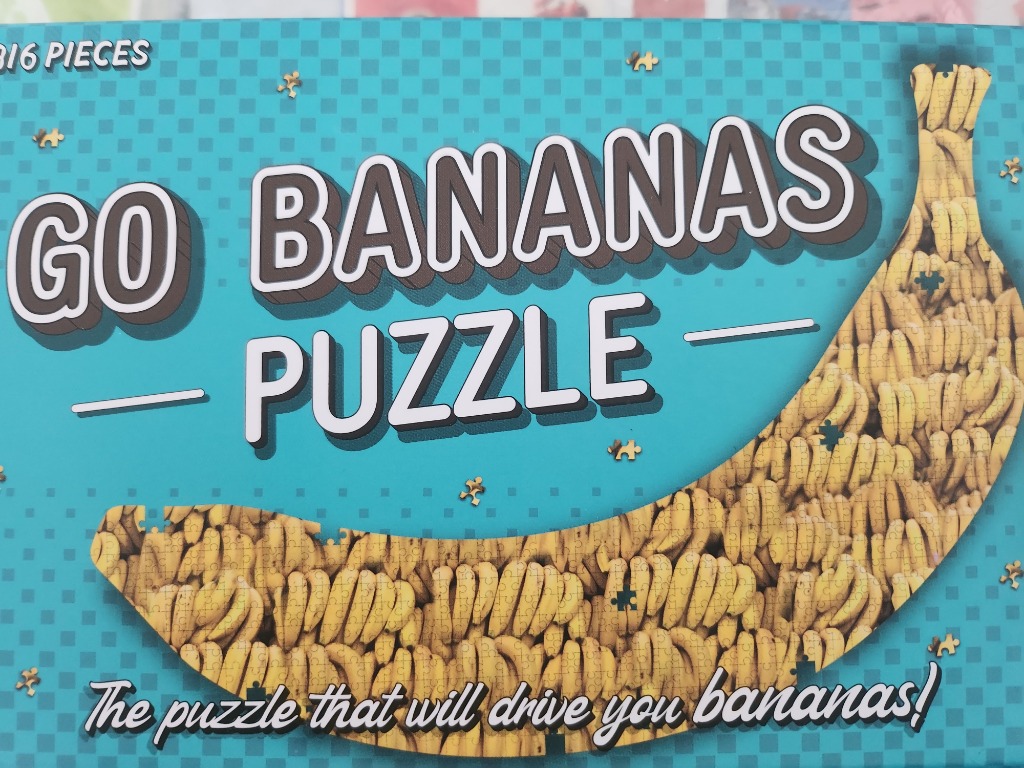 A giant banana shape made of many smaller bananas on a teal checkered background with the text GO BANANAS PUZZLE.