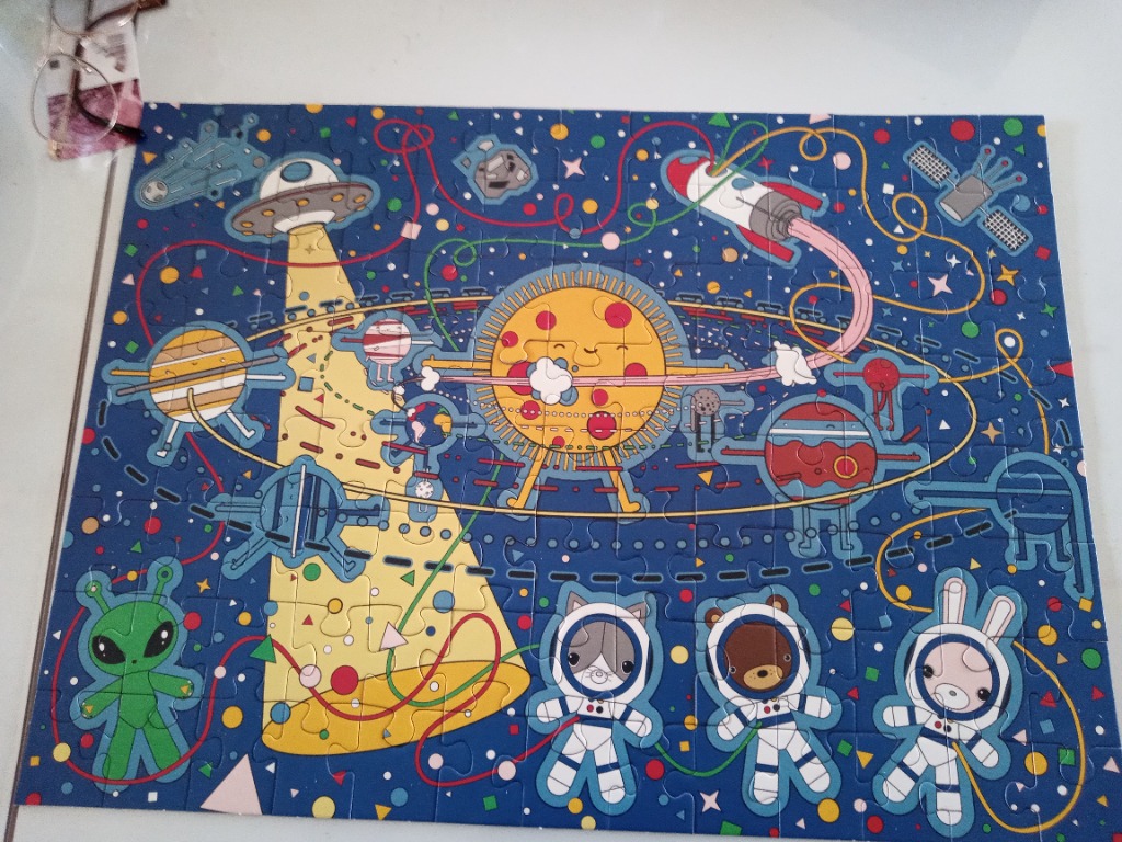Cartoon outer space illustration with planets, a smiling sun, astronauts, and a UFO on a dark blue background.