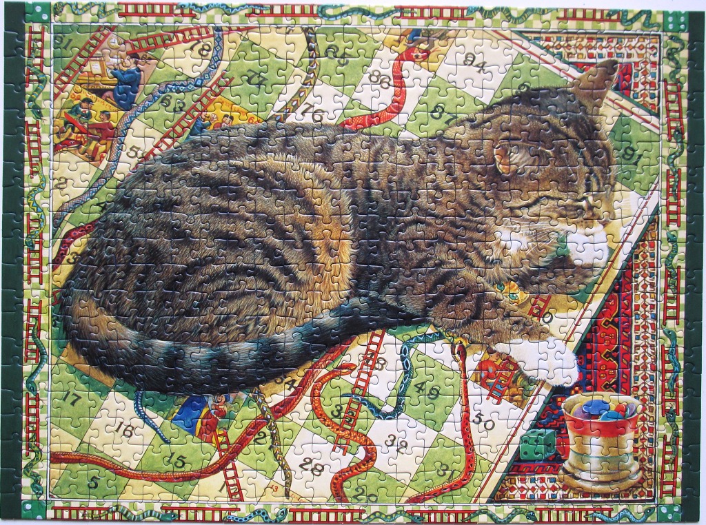 A tabby cat sleeping on a Snakes and Ladders game board