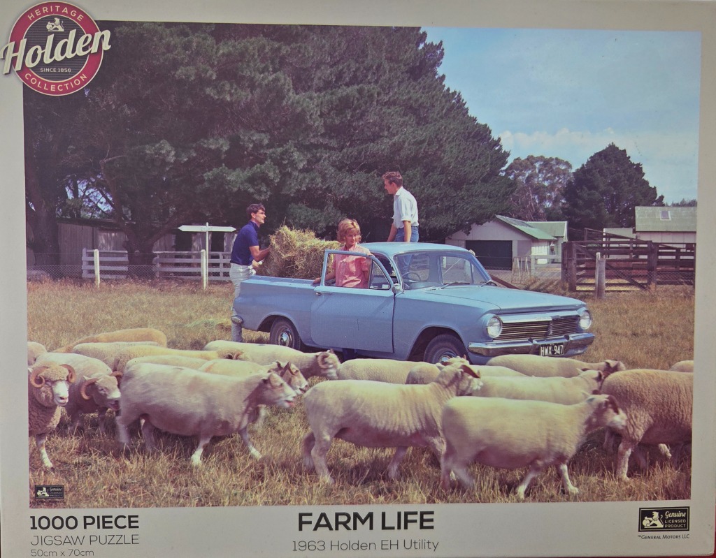 A 1963 light blue utility vehicle in a paddock with three people loading hay, surrounded by a flock of sheep.
