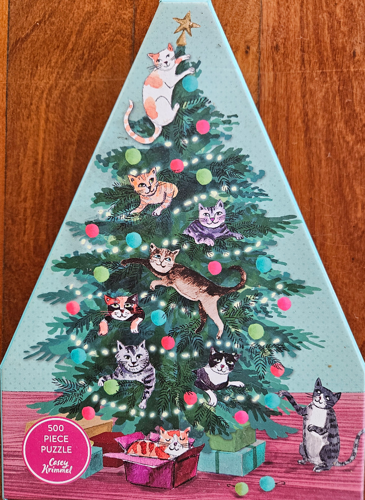 A triangular illustration of a Christmas tree filled with playful cats and colorful ornaments.