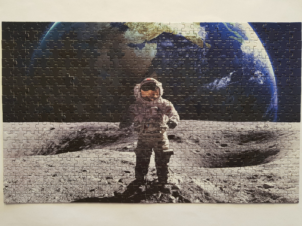 An astronaut standing on the lunar surface with the blue Earth hanging in the black space above.