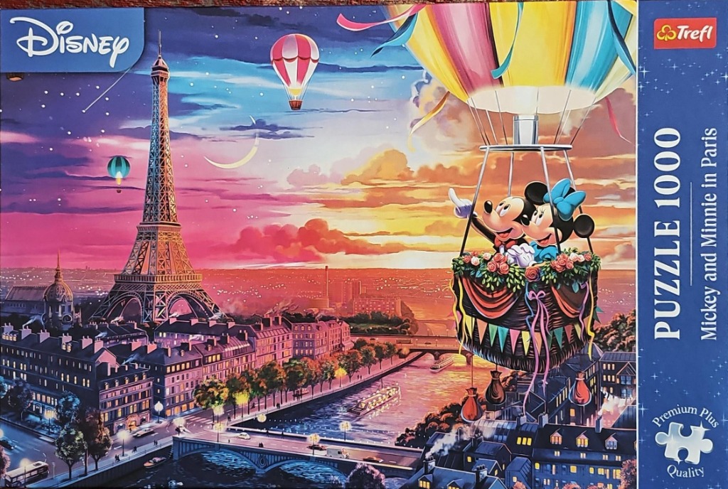 Mickey and Minnie Mouse riding in a hot air balloon over a sunset cityscape of Paris featuring the Eiffel Tower.