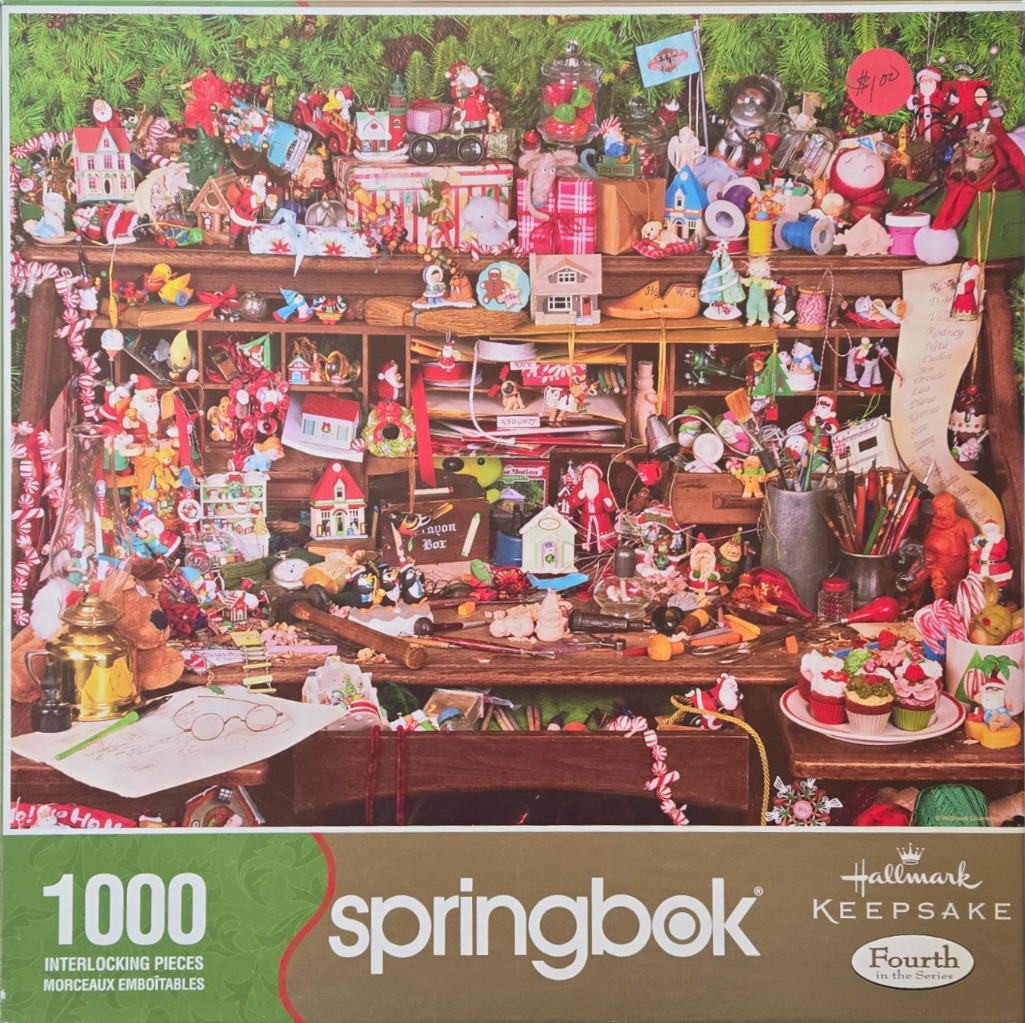 A cluttered wooden desk overflowing with Christmas-themed decorations, ornaments, and holiday crafts.