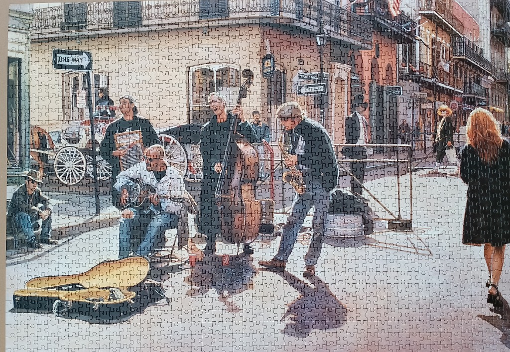 A jazz trio performing on a New Orleans street corner with a woman walking by.