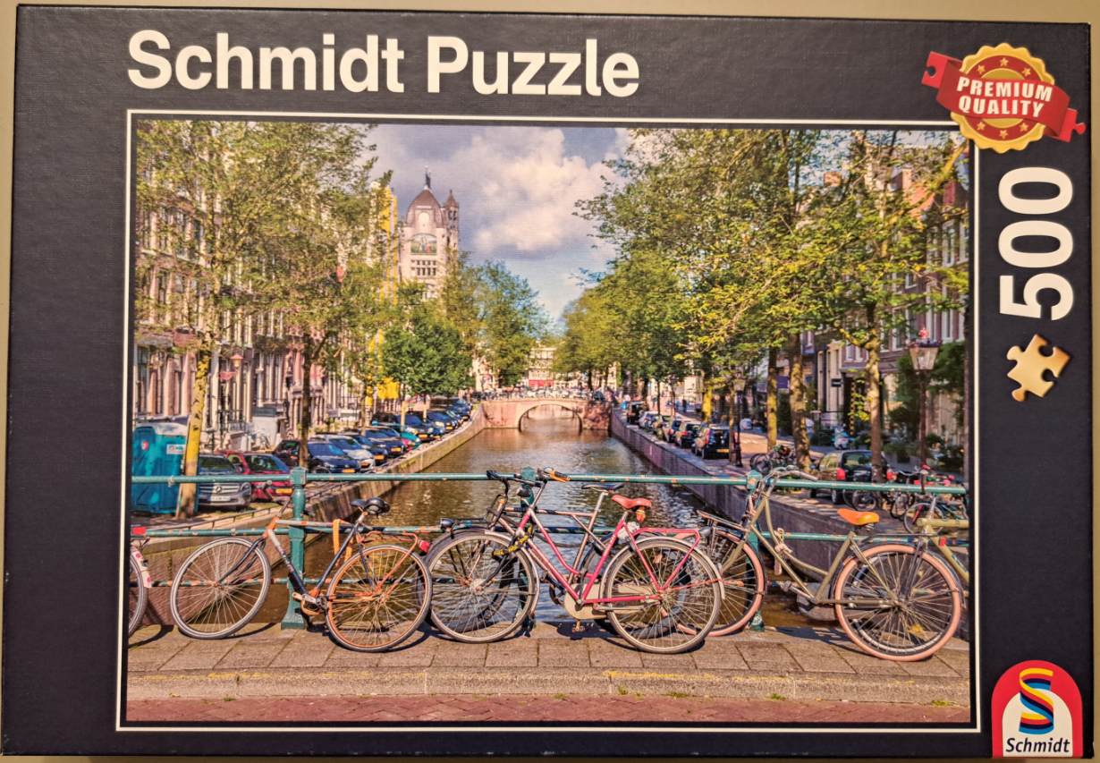 Three bicycles lined up along a bridge railing overlooking a canal in Amsterdam.