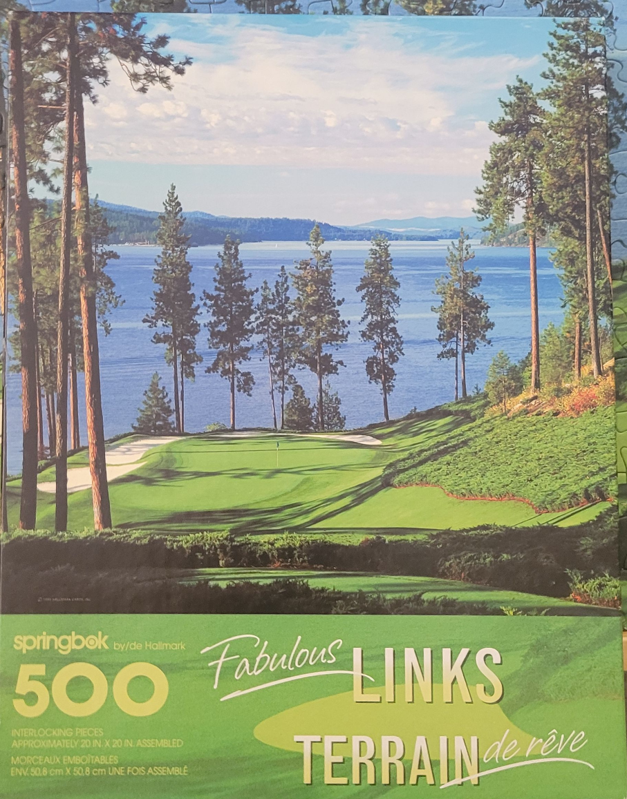 A peaceful golf course hole overlooking a calm, deep blue lake surrounded by tall pine trees and distant hills.