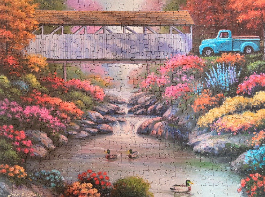 A vintage blue pickup truck parked near a wooden covered bridge over a stream with ducks and colorful autumn flowers.