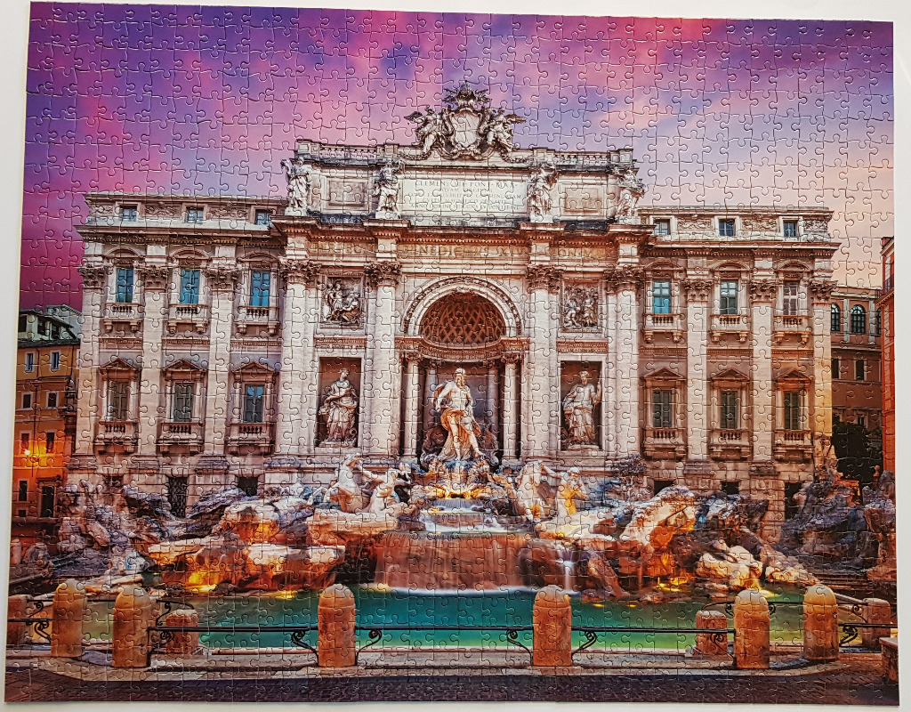 The Trevi Fountain in Rome under a vibrant purple and orange sunset sky.