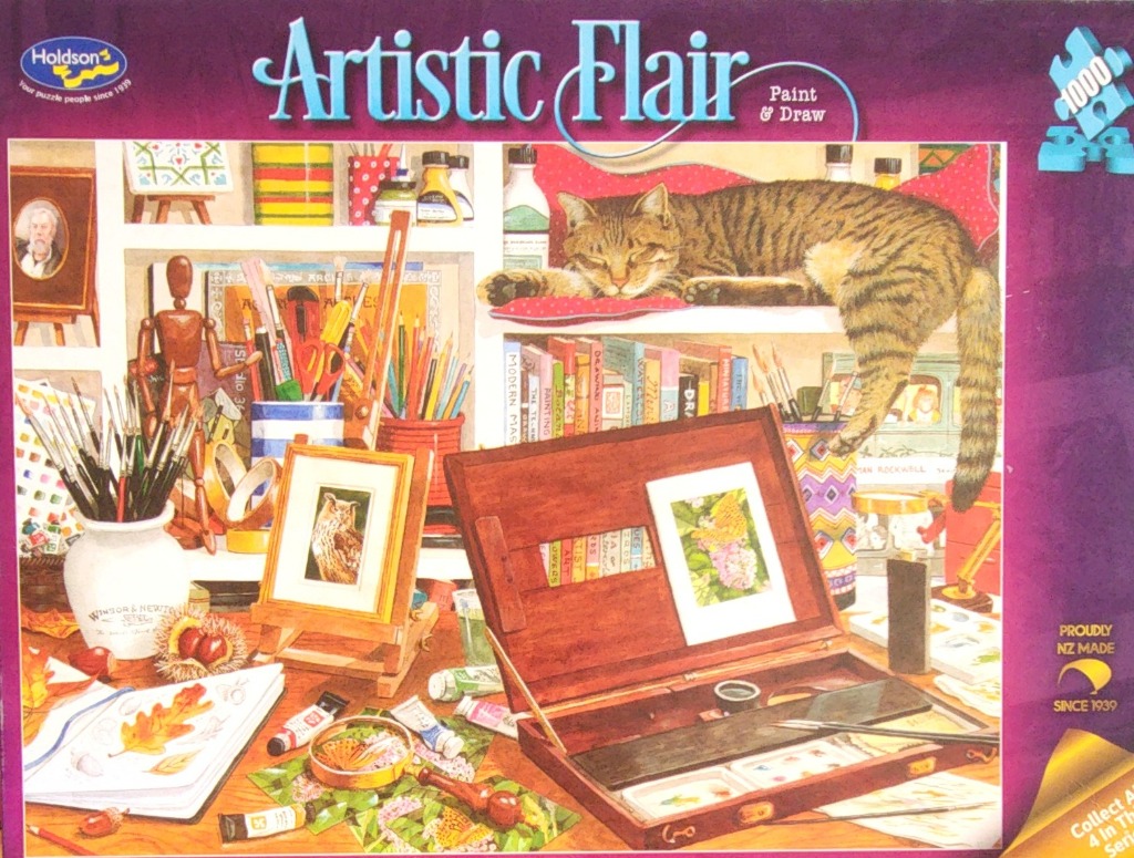 A cozy artist's studio cluttered with supplies and a tabby cat sleeping on a shelf.