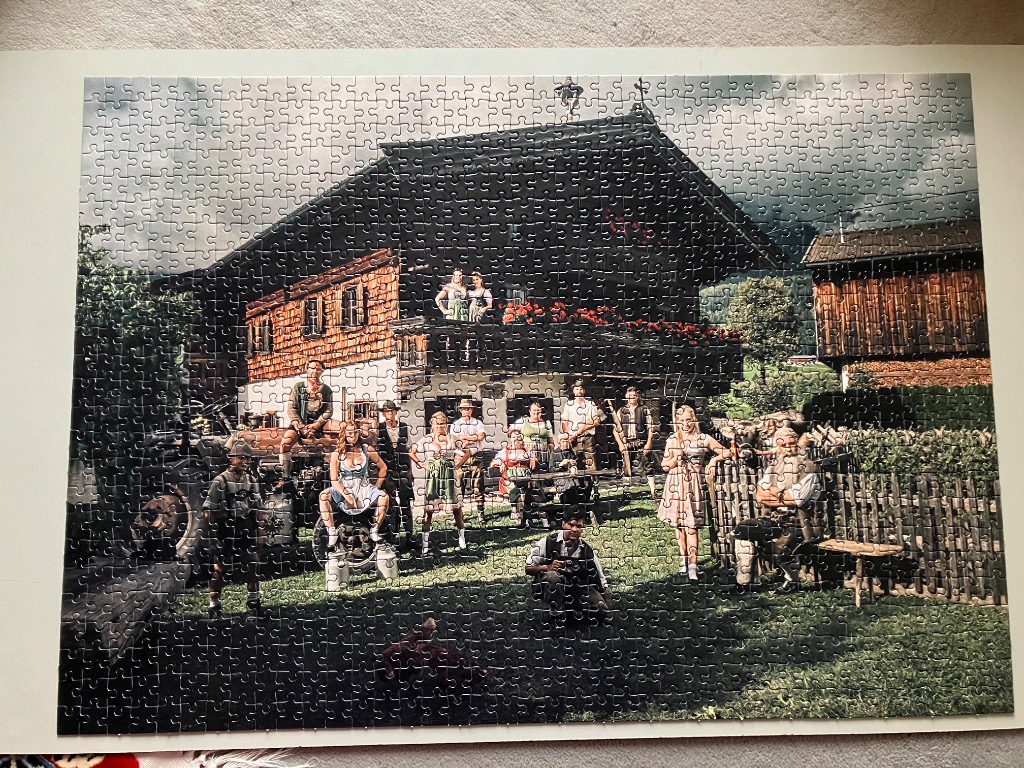 A group of people in traditional Bavarian clothing posing in front of a rustic alpine farmhouse.