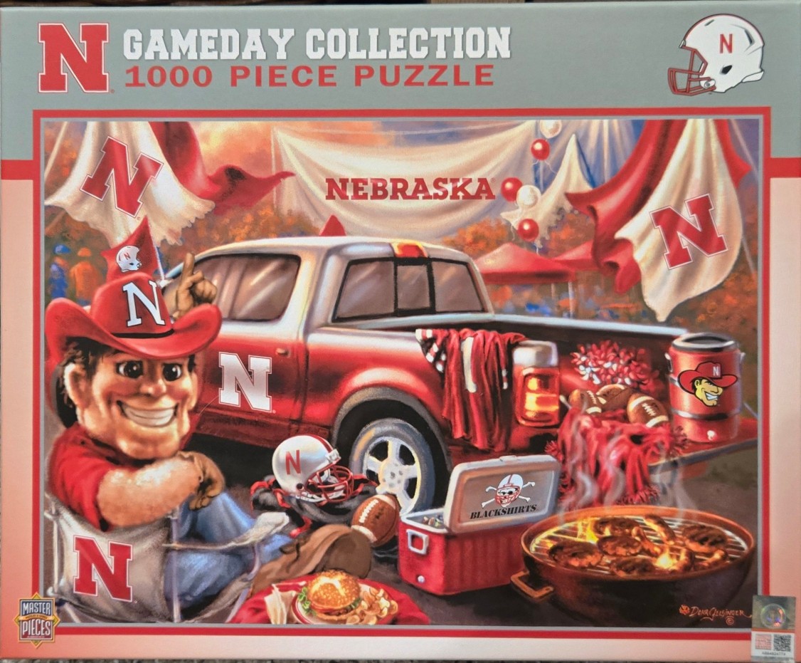 University of Nebraska football tailgate scene with a mascot in a red cowboy hat and a red pickup truck.