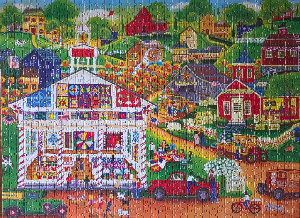 A folk art style illustration of a vibrant country fair with a large quilt-covered barn and village scenery.
