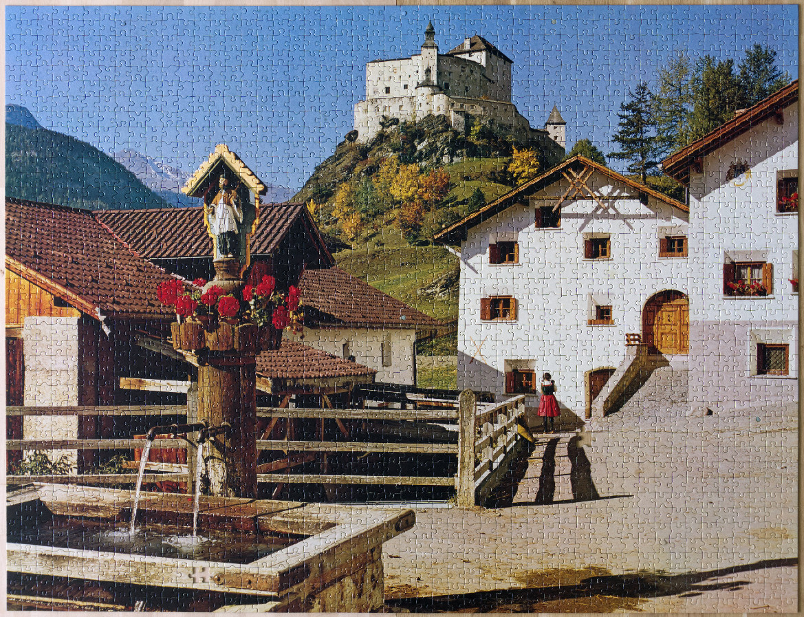 A sunny European village scene with a historic stone castle on a hill in the background and a fountain in the foreground.