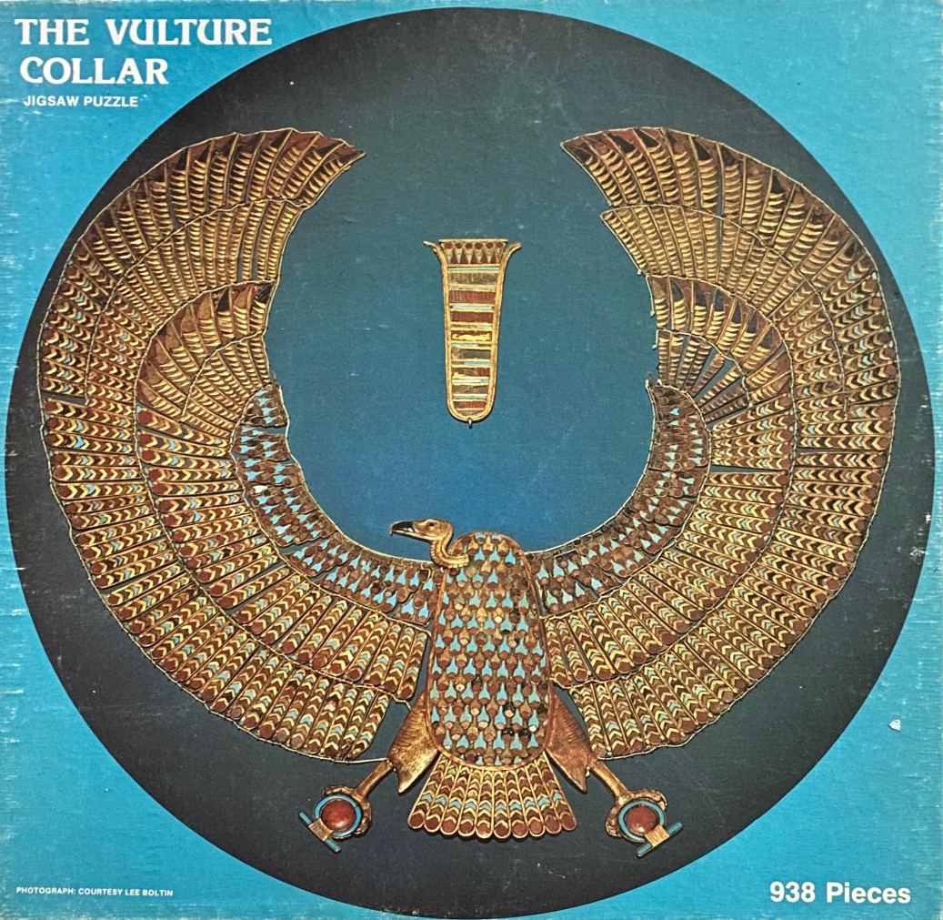 An ornate golden Egyptian vulture pectoral ornament centered on a circular teal background.
