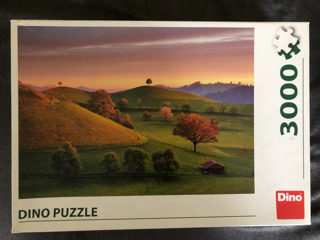 A scenic photograph of rolling green hills at sunset with a small hut and trees.