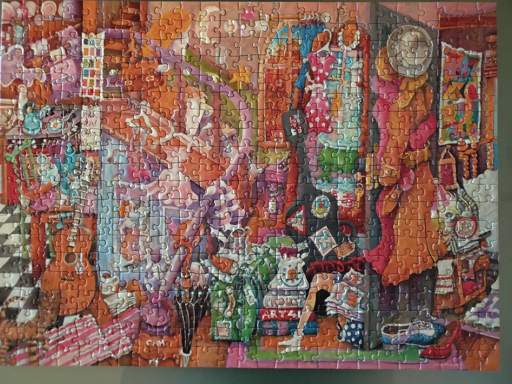 An eccentric, colourful illustration of a cluttered bohemian art studio filled with musical instruments and clothes.