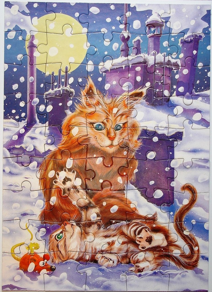 A fluffy ginger cat watches a small tabby kitten play with a toy mouse on a snowy rooftop under a full moon.