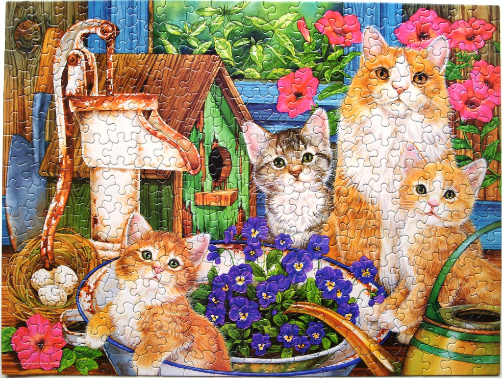 Four kittens with a vintage water pump and flowers in a garden setting.