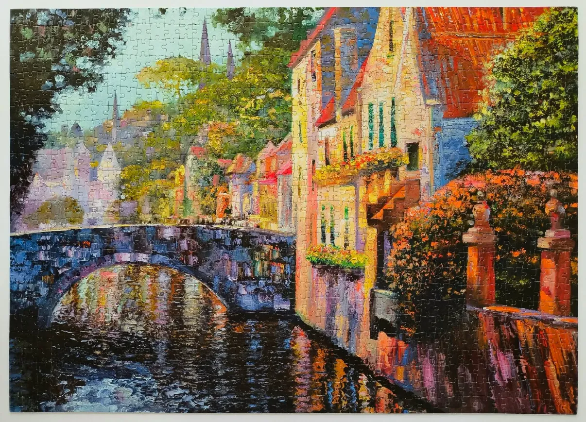 Impressionist oil painting of a stone bridge over a canal in a European town with red-roofed buildings.