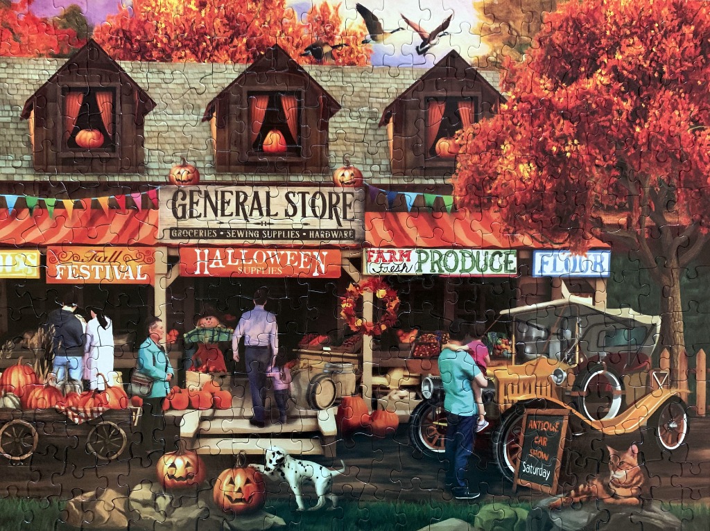 A charming general store scene decorated for autumn with pumpkins, fall foliage, and an antique car.