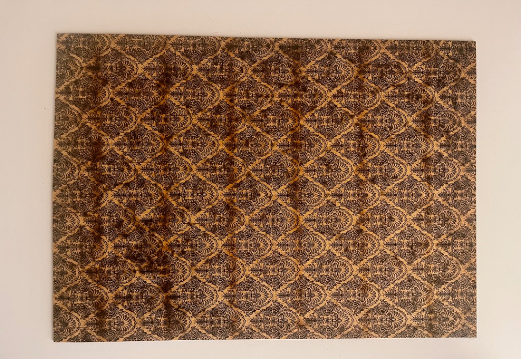 A rectangular damask pattern with dark brown ornate floral motifs over a distressed, aged yellow background.