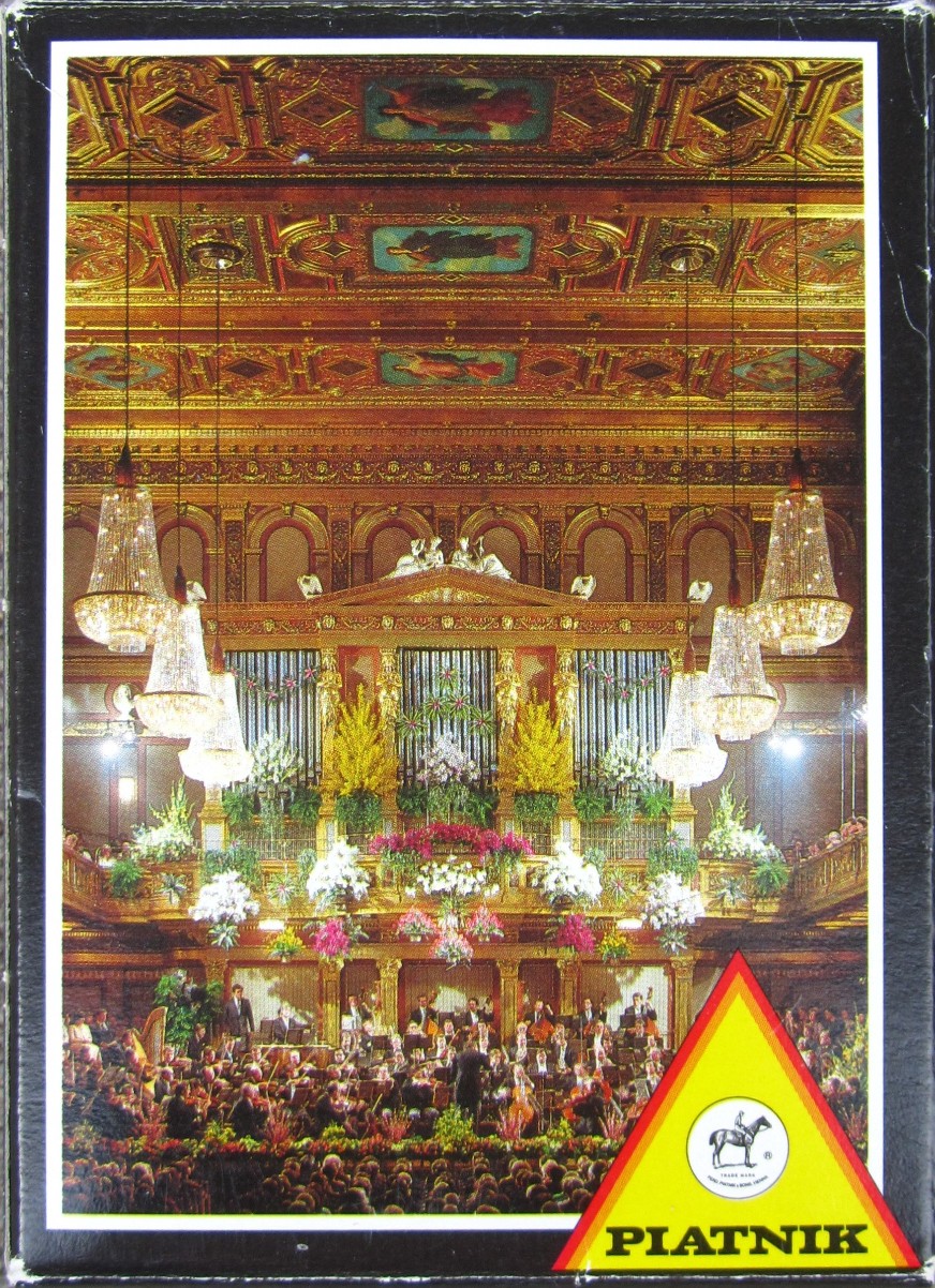 The ornate interior of a concert hall with a large pipe organ, orchestra, and crystal chandeliers.