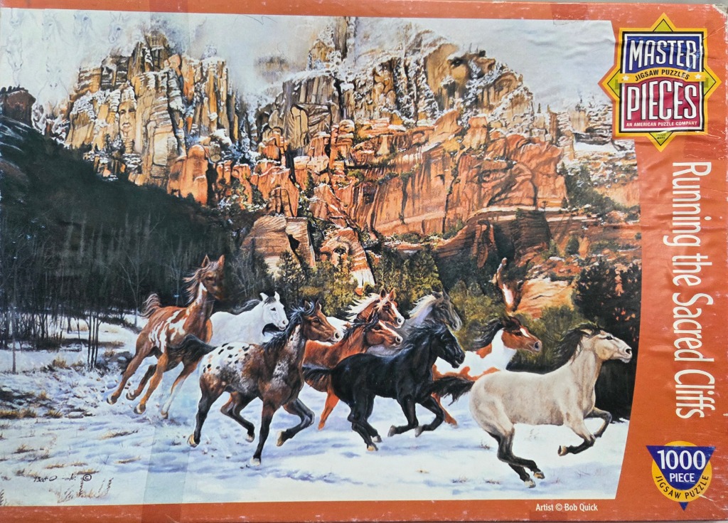 A herd of horses running through a snowy landscape with tall, rocky canyon cliffs in the background.