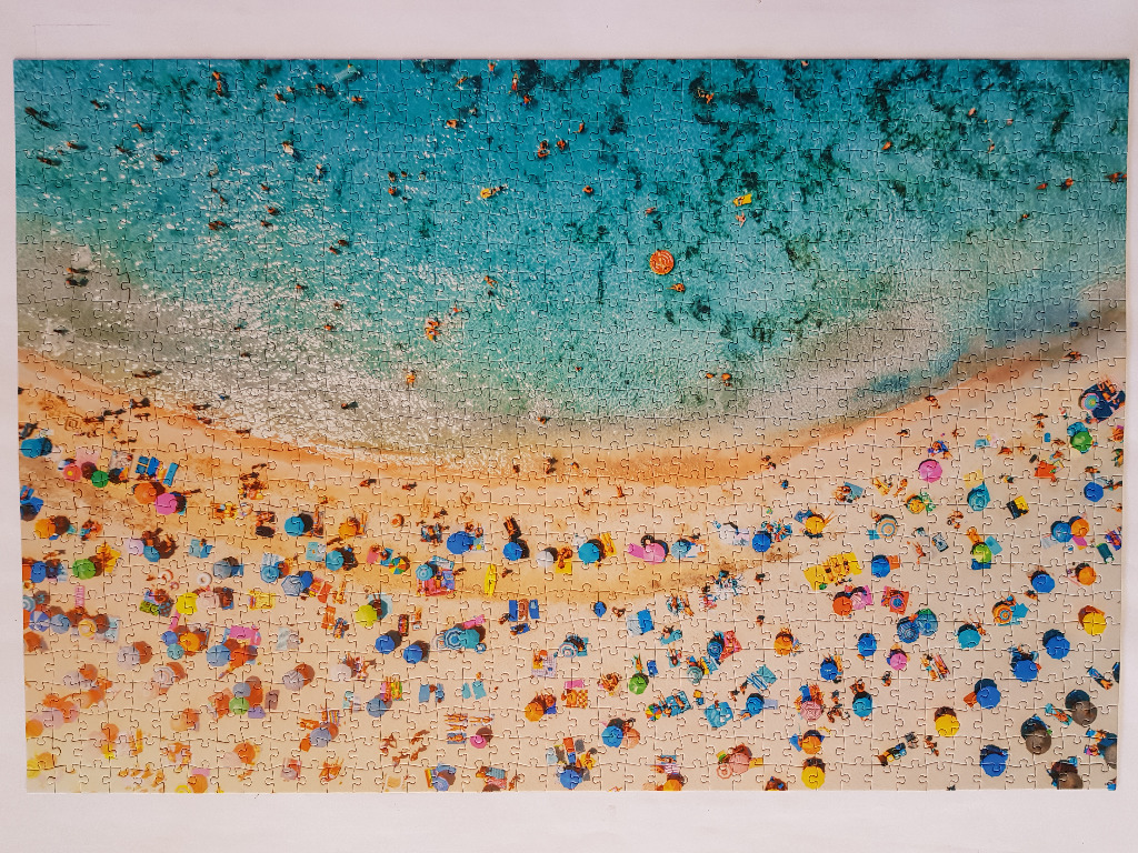 Aerial view of a crowded sandy beach with colorful umbrellas and clear blue water