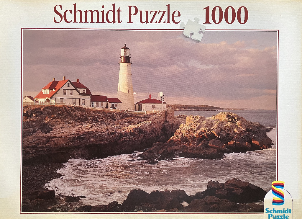 A lighthouse and keeper's house on a rocky coastline at sunset.
