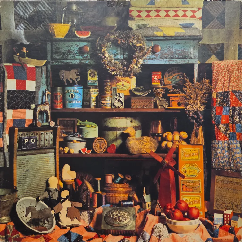 A collection of rustic Americana, including quilts, antique tins, and wooden folk art, arranged on shelves.