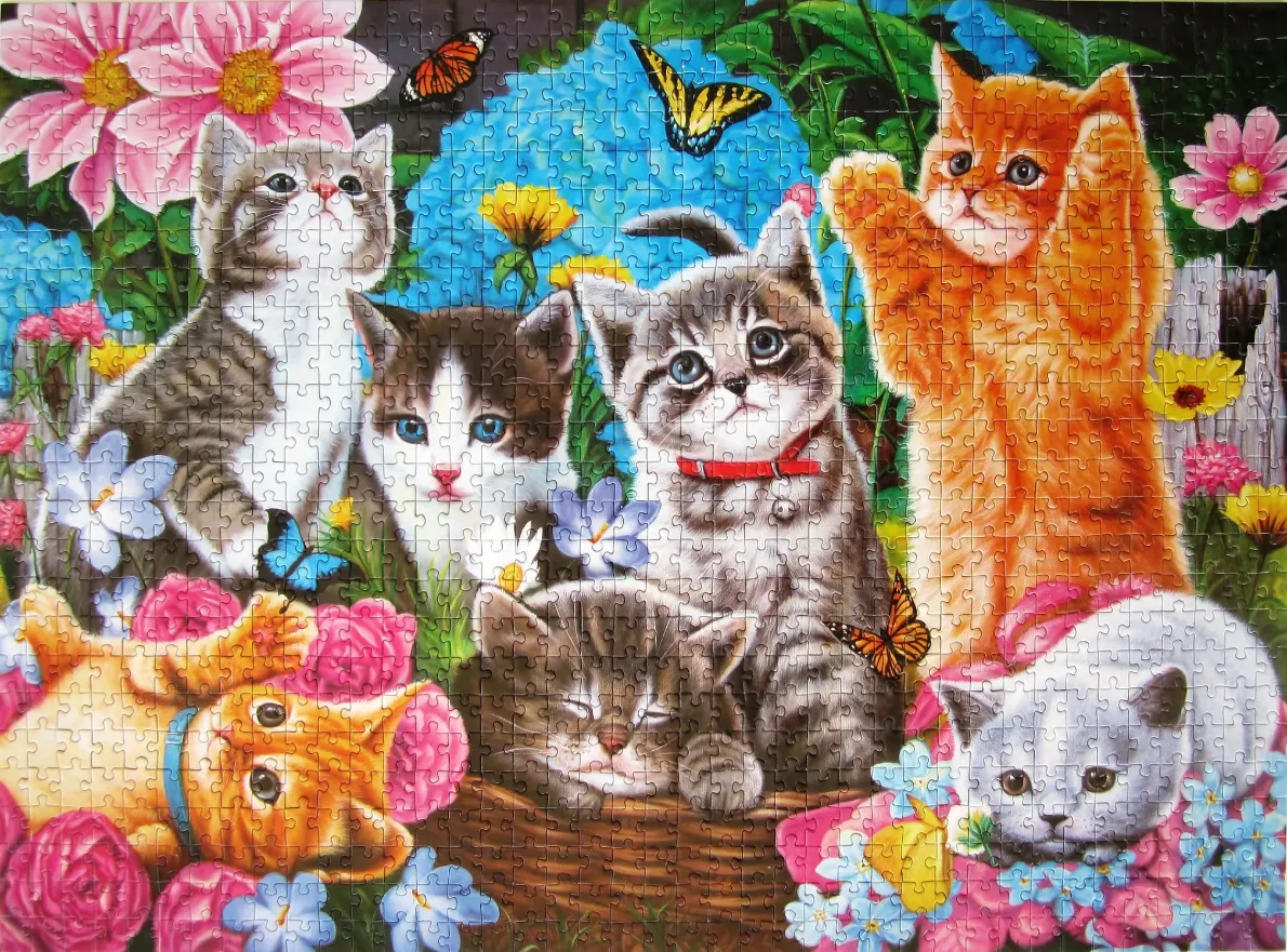 A group of six adorable kittens playing and resting in a vibrant flower garden.