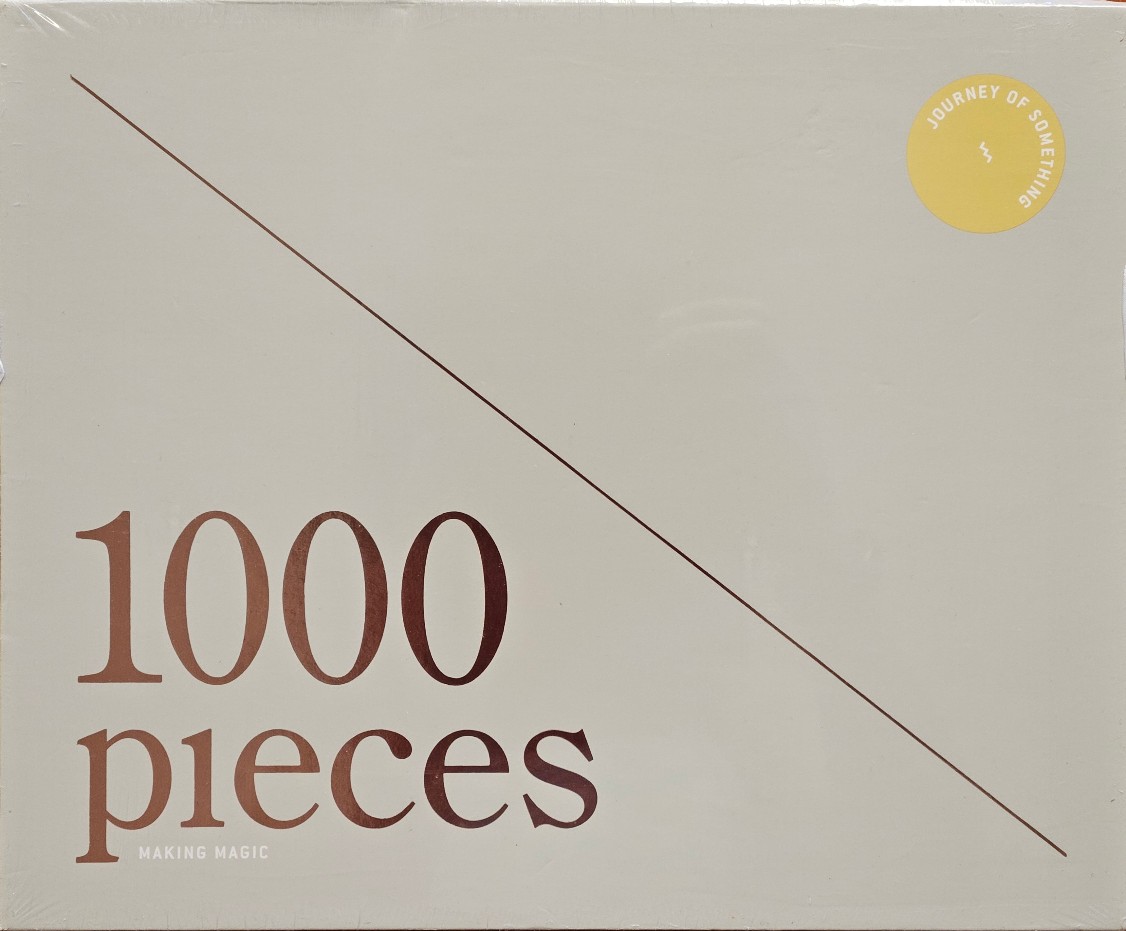 Minimalist design with the text '1000 pieces' in a copper-toned serif font against a solid beige background.