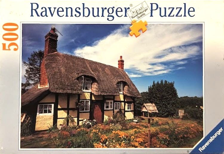 A traditional English thatched-roof cottage with half-timbered walls and a vibrant flower garden.