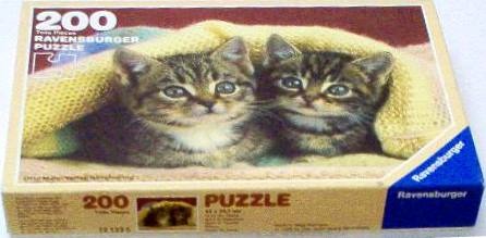 Two tabby kittens peeking out from a soft yellow knitted blanket.