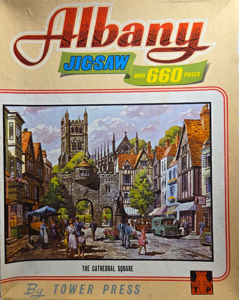 Painting of a historic European town square with timber-framed buildings and a stone cathedral gatehouse.