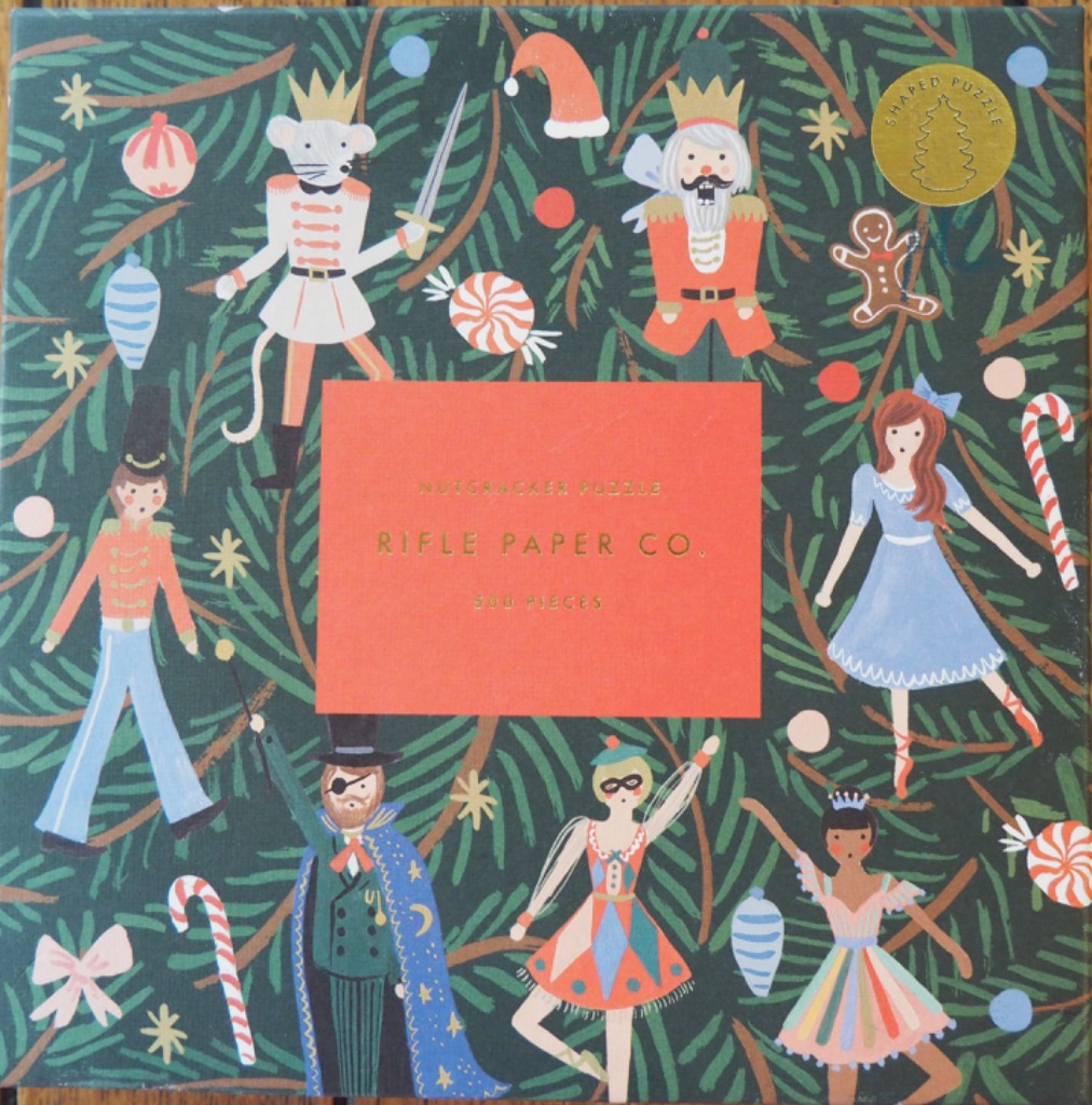 Illustration of Nutcracker ballet characters arranged among pine boughs and Christmas ornaments.