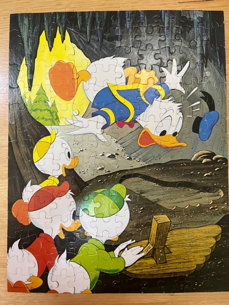 Donald Duck and his three nephews exploring a dark cavern