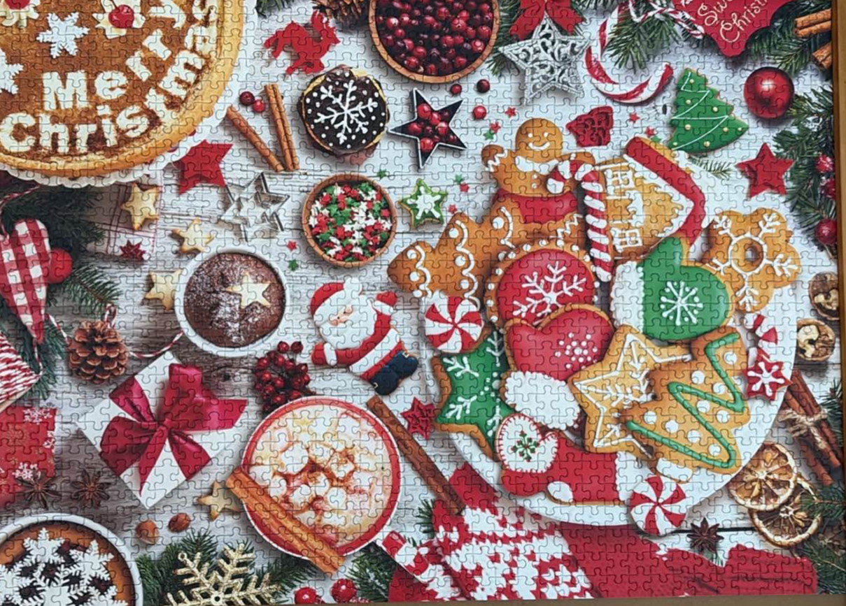 A festive overhead view of Christmas cookies, hot cocoa, and holiday decorations on a light wooden table.
