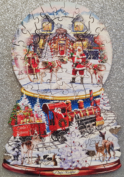 A whimsical snow globe decoration featuring Santa Claus at his workshop and the Santa Express train.