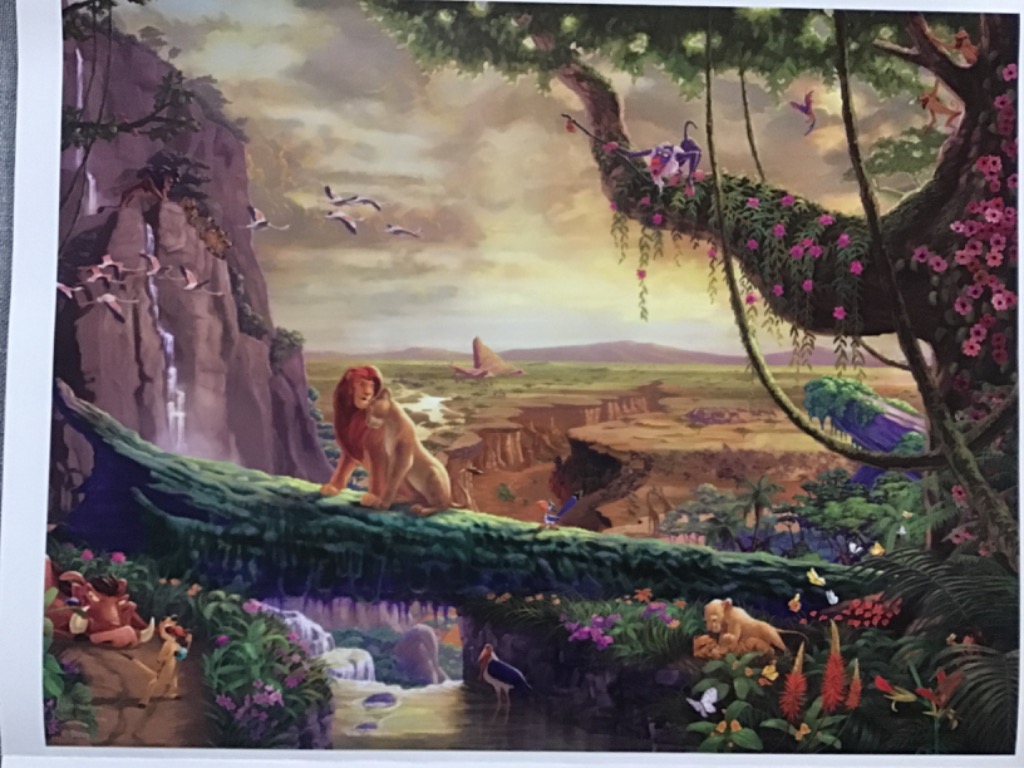 A pair of lions resting on a log overlooking a vast savanna landscape populated by jungle animals.