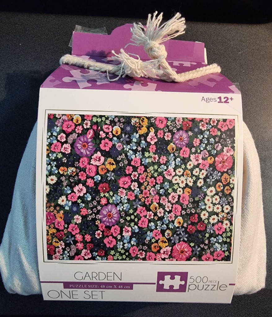 A dense pattern of colorful flowers in pink, yellow, and purple against a dark background.
