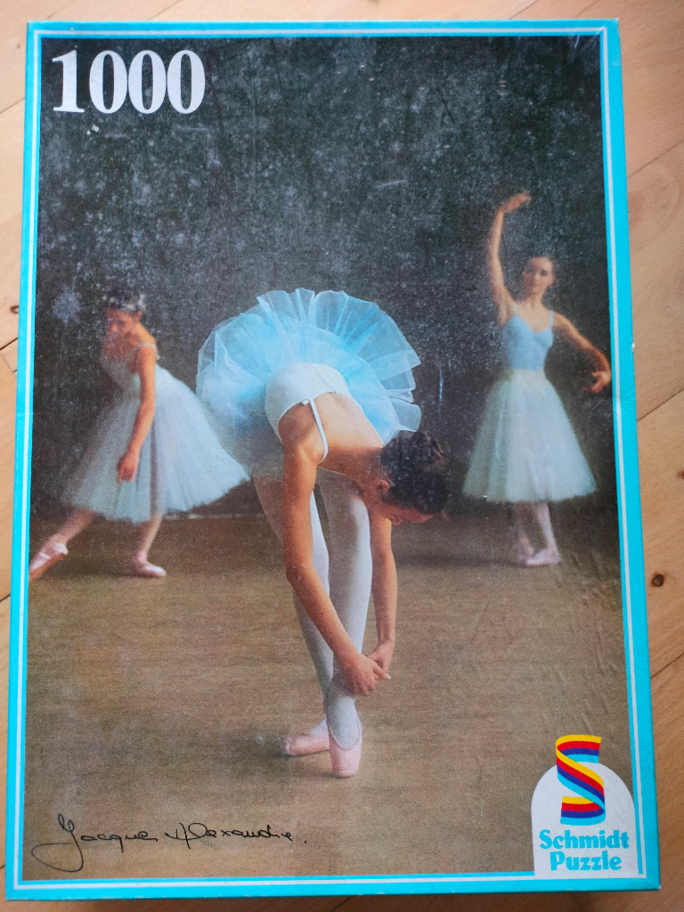 Three ballet dancers in pale blue tutus pose in a dark, atmospheric studio setting.