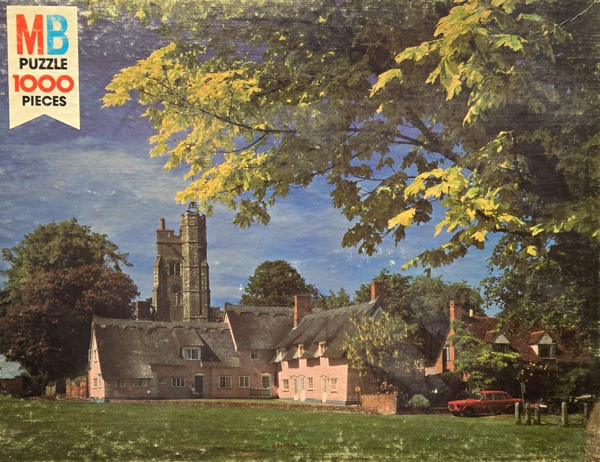 A village scene featuring a pink-walled cottage with a thatched roof, an ancient stone church tower, and a red car.