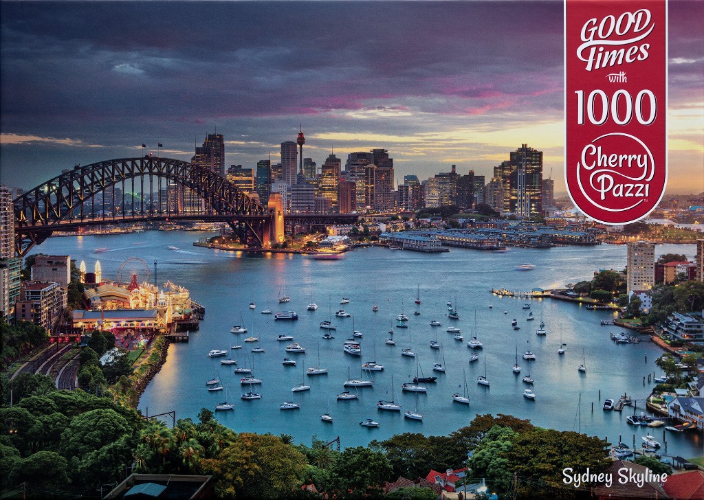 A twilight view of the Sydney Harbour Bridge and city skyline across the water with many sailboats.
