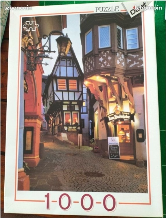 A narrow, cobblestone European street scene flanked by historic timber-framed buildings at dusk.